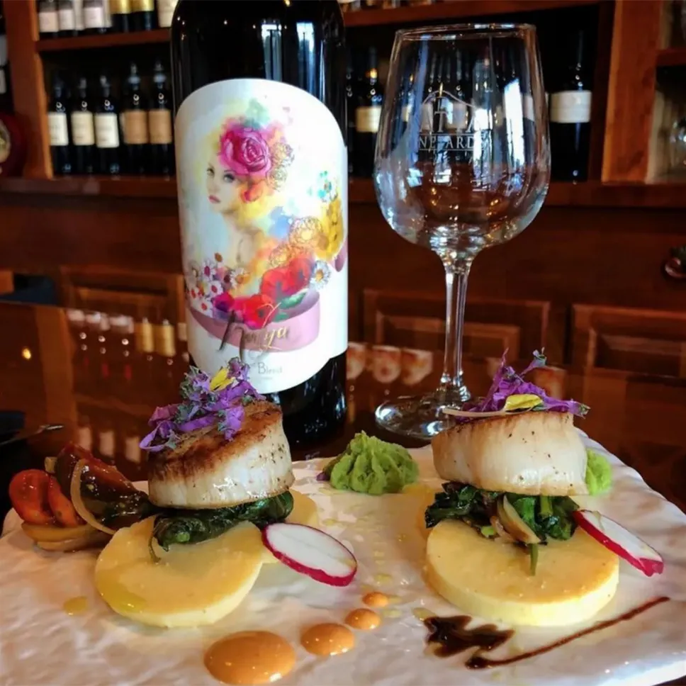 Seared scallops plated beside a bottle of Katya wine